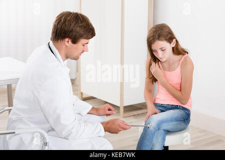 Young Male Doctor Checking Knee Reflex On Child Patient In Clinic Stock Photo