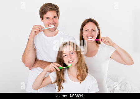Parent With Their Daughter Brushing Teeth Together Stock Photo