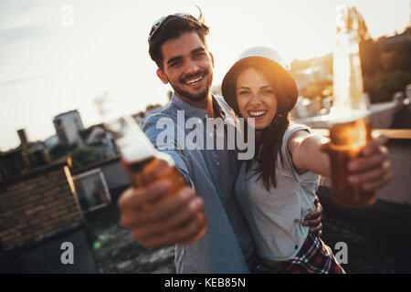 Young happy couple toasting with beer outdoors Stock Photo