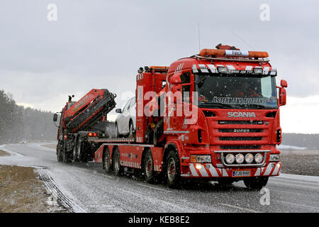 SALO, FINLAND - MARCH 20, 2016: Truck and car are being towed by a heavy duty tow truck in snowfall. Heavy duty towing requires special skills and equ Stock Photo