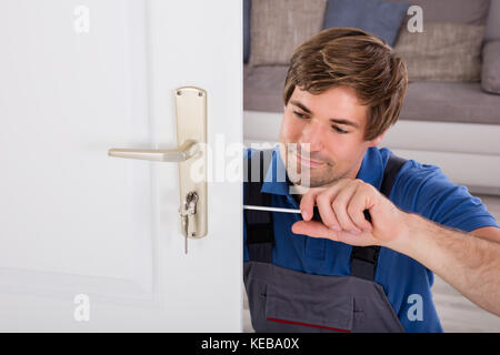 Handyman Fitting A New Door Using A Screwdriver At Home Stock Photo