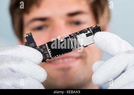 Close-up Of A Happy Man Holding Smart Phone Circuit Board Wearing Glove Stock Photo