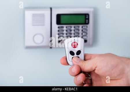 Close-up Of Person Hand Using Remote To Operate Security System Stock Photo