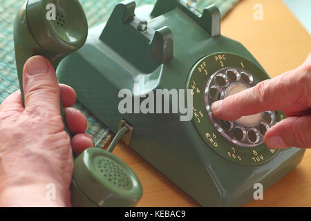 An older man dials a number on a vintage landline phone. Stock Photo