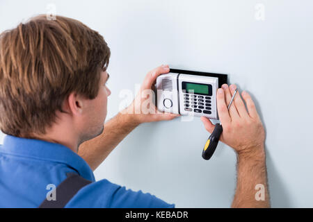 Young Male Technician Installing Security System Using Screwdriver Stock Photo