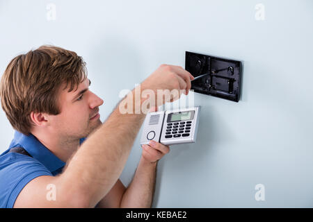Young Male Technician Installing Security System Using Screwdriver Stock Photo