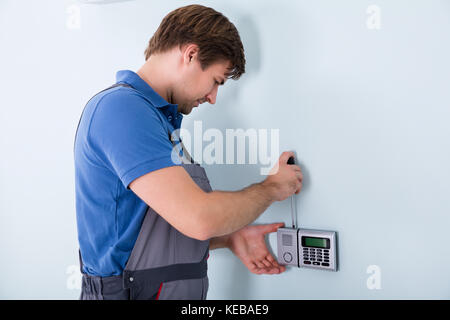 Young Male Repairman Fixing Security System Using Screwdriver At Home Stock Photo