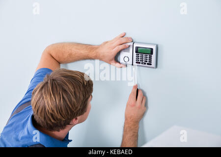 Young Male Repairman Fixing Security System Using Screwdriver At Home Stock Photo