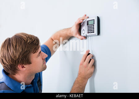 Young Male Repairman Fixing Security System Using Screwdriver At Home Stock Photo