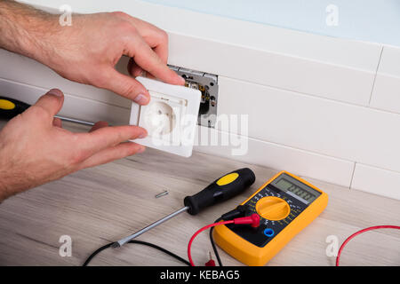 Close-up Of Person's Hand Installing Socket On Wall At Home Stock Photo