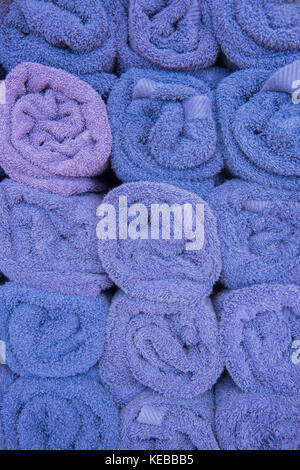 Full frame of rolled purple towels organised in rows with end facing forward. Stock Photo