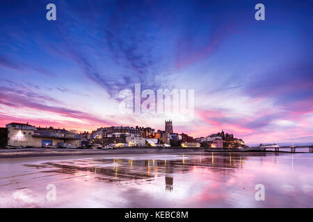 Cromer In Pink - Panoramic view of British seaside town of Comer. Fantastic sunset colours of pinks and purples with reflections of the town in the wa Stock Photo