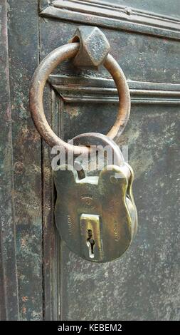 Old rusty padlock on bronze gate Stock Photo