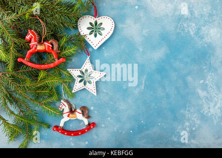 Christmas and New Year blue background with fir branches and Christmas toys - horses, a star and a heart. Top view Stock Photo