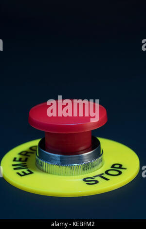 Big red button on dark background - metaphor for 'Finger on the Button', possible finger on nuclear button, & concept of bringing things to a stop. Stock Photo