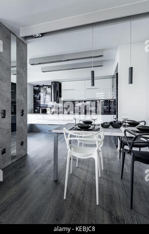 Apartment with open kitchen and table with new design black and white chairs Stock Photo