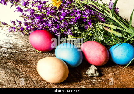 A bouquet of blooming purple wild flowers and painted Easter eggs on a straw mat Stock Photo