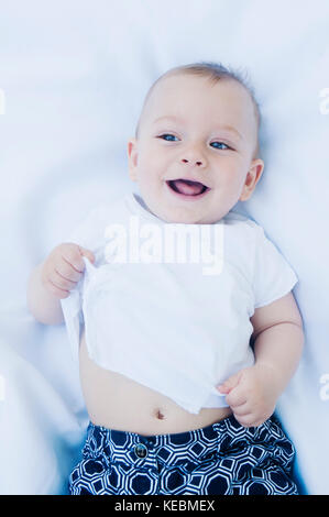 High Angle View of Smiling Baby Boy Laying on His Back Stock Photo