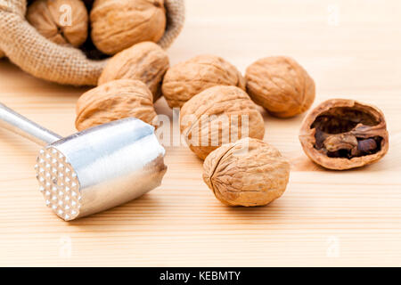 Walnuts kernels and whole walnuts on wooden background. Whole and chopped walnuts on wooden background. Walnuts kernels and nutcracker. Selective focu Stock Photo