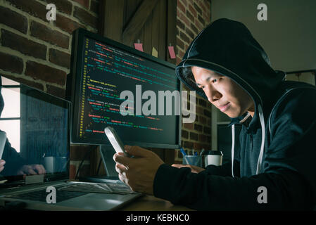 professional young male programmer using mobile cell phone spread virus and hoping to get many money. Stock Photo