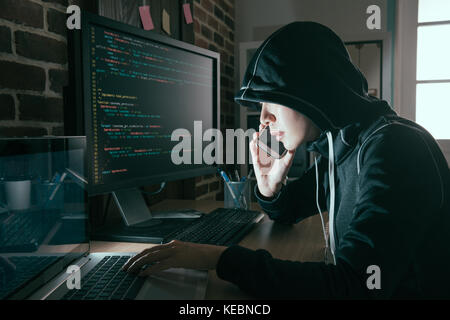 professional hacker woman hidden face using mobile cell phone talking with victim request ransom when she spread bad data virus online. Stock Photo