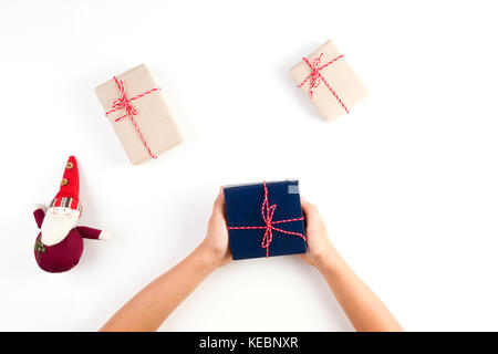 Top view of kid hands holding a present. Gift boxes packed in craft paper and christmas decoration on white table Stock Photo