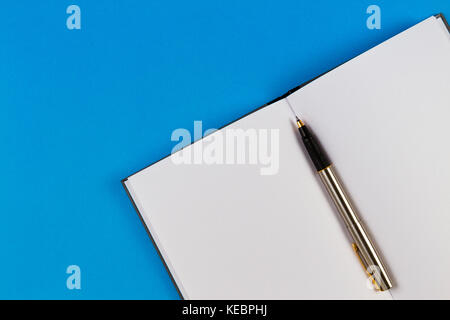 Open notebook with two blank pages and pen on blue background Stock Photo