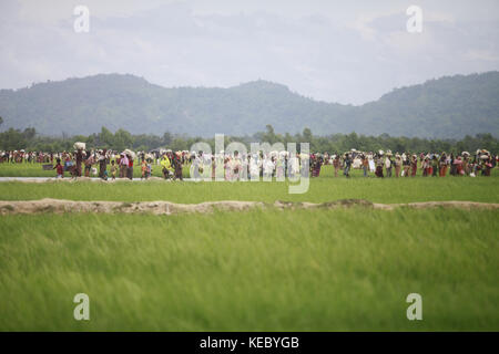 Ukhiya, Cox's Bazar, Bangladesh. 19th Oct, 2017. Rohingya Muslims, who spent four days in the open after crossing over from Myanmar into Bangladesh, carry their children and belongings after they were allowed to proceed towards a refugee camp, at Anjuman Para, Ukhiya, Bangladesh, October 19, 2017. More than 580,000 refugees have arrived in Bangladesh since Aug. 25, when Myanmar security forces began a scorched-earth campaign against Rohingya villages. Credit: ZUMA Press, Inc./Alamy Live News Stock Photo