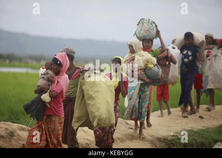 Ukhiya, Cox's Bazar, Bangladesh. 19th Oct, 2017. Rohingya Muslims, who spent four days in the open after crossing over from Myanmar into Bangladesh, carry their children and belongings after they were allowed to proceed towards a refugee camp, at Anjuman Para, Ukhiya, Bangladesh, October 19, 2017. More than 580,000 refugees have arrived in Bangladesh since Aug. 25, when Myanmar security forces began a scorched-earth campaign against Rohingya villages. Credit: ZUMA Press, Inc./Alamy Live News Stock Photo