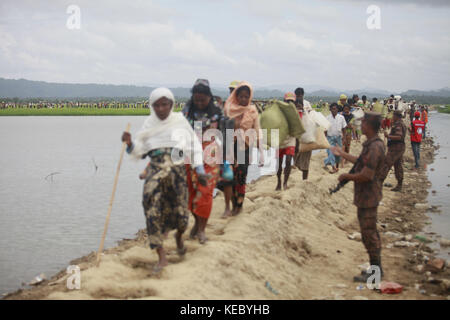 Ukhiya, Cox's Bazar, Bangladesh. 19th Oct, 2017. Rohingya Muslims, who spent four days in the open after crossing over from Myanmar into Bangladesh, carry their children and belongings after they were allowed to proceed towards a refugee camp, at Anjuman Para, Ukhiya, Bangladesh, October 19, 2017. More than 580,000 refugees have arrived in Bangladesh since Aug. 25, when Myanmar security forces began a scorched-earth campaign against Rohingya villages. Credit: ZUMA Press, Inc./Alamy Live News Stock Photo