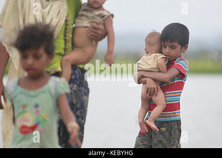 Ukhiya, Cox's Bazar, Bangladesh. 19th Oct, 2017. Rohingya Muslims, who spent four days in the open after crossing over from Myanmar into Bangladesh, carry their children and belongings after they were allowed to proceed towards a refugee camp, at Anjuman Para, Ukhiya, Bangladesh, October 19, 2017. More than 580,000 refugees have arrived in Bangladesh since Aug. 25, when Myanmar security forces began a scorched-earth campaign against Rohingya villages. Credit: ZUMA Press, Inc./Alamy Live News Stock Photo