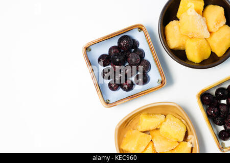 sliced ripe mango cubes and blueberry in a bowl on a white background - Top view Stock Photo