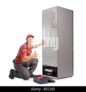 Repairman fixing a refrigerator and making a thumb up sign isolated on white background Stock Photo