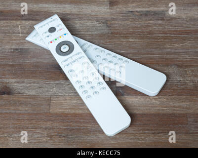 Two white remotes on a wooden table Stock Photo