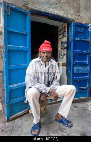 Man in blue sandals & red hat, Rue Oudja, Essaouira, Morocco Stock Photo