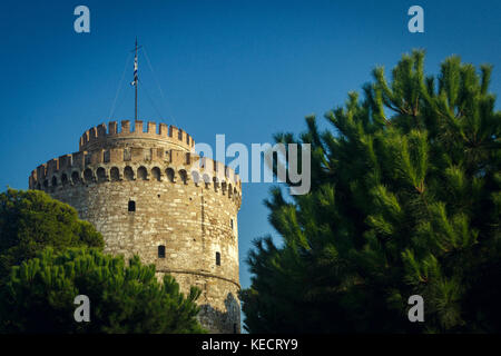 Main sights of the Greek city white tower among green trees and against the blue sky, Greece, Thessaloniki Stock Photo