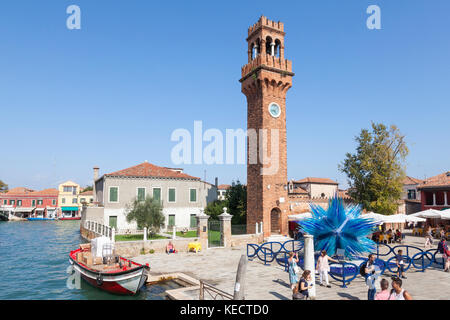 Elevated view of Campo Santo  Stefano and the Comet Glass Star, Murano, Venice, Italy with tourists and a colorful red boat in the canal Stock Photo