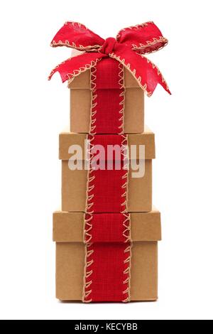 Stacked brown Christmas gift boxes wrapped with rustic red bow and ribbon, isolated on white Stock Photo
