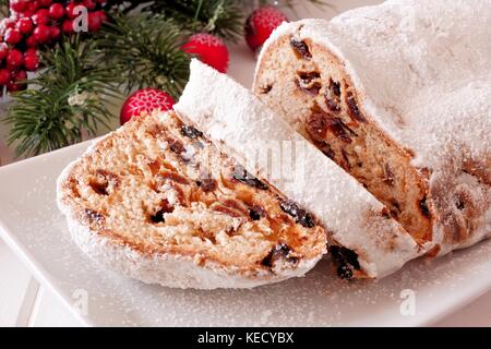 Traditional homemade stollen dessert with cut slices on a plate with Christmas decor Stock Photo