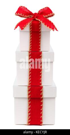 Stacked white Christmas gift boxes wrapped with rustic red bow and ribbon, isolated on white Stock Photo