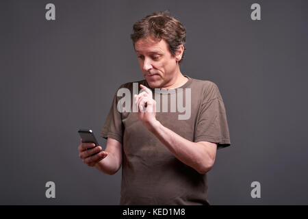 A middle age man standing and using a smartphone Stock Photo