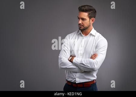 A handsome confident young man standing seriously in a white shirt. Stock Photo
