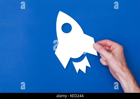 male hand holding a rocket icon symbol against a blue background Stock Photo