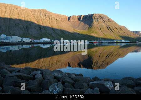 Reflections of buildings and brown mountains on water in fjord of quaint fishing town of Isafjordur, Ísafjarðarbær, Westfjords, North West Iceland Stock Photo
