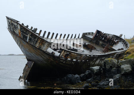 Old shipwreck stranded on shore with decaying wood on remote Flatey Island in Iceland Stock Photo