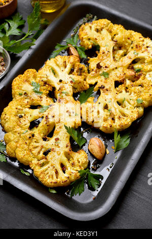Baked cauliflower steaks with herbs and spices on baking sheet Stock Photo
