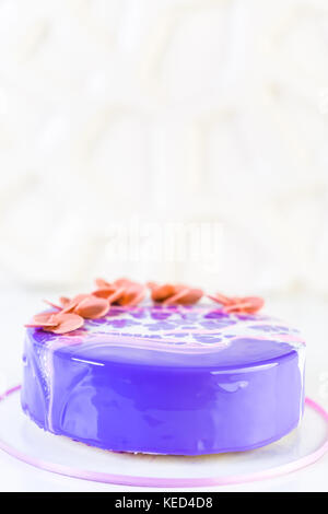 Pastre shef making mousse cake with purple mirror glaze and decorated with chocolate pink flowers. Stock Photo