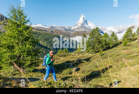 Hiker on 5-lakes hiking trail, snow-covered Matterhorn in the back, Valais, Switzerland Stock Photo