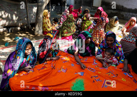 Rural women make Nakshi Kantha, a type of embroidered quilt at a village in Jessore. Bangladesh. Stock Photo