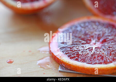 Closeup of a fresh slice of blood orange on a cutting board Stock Photo